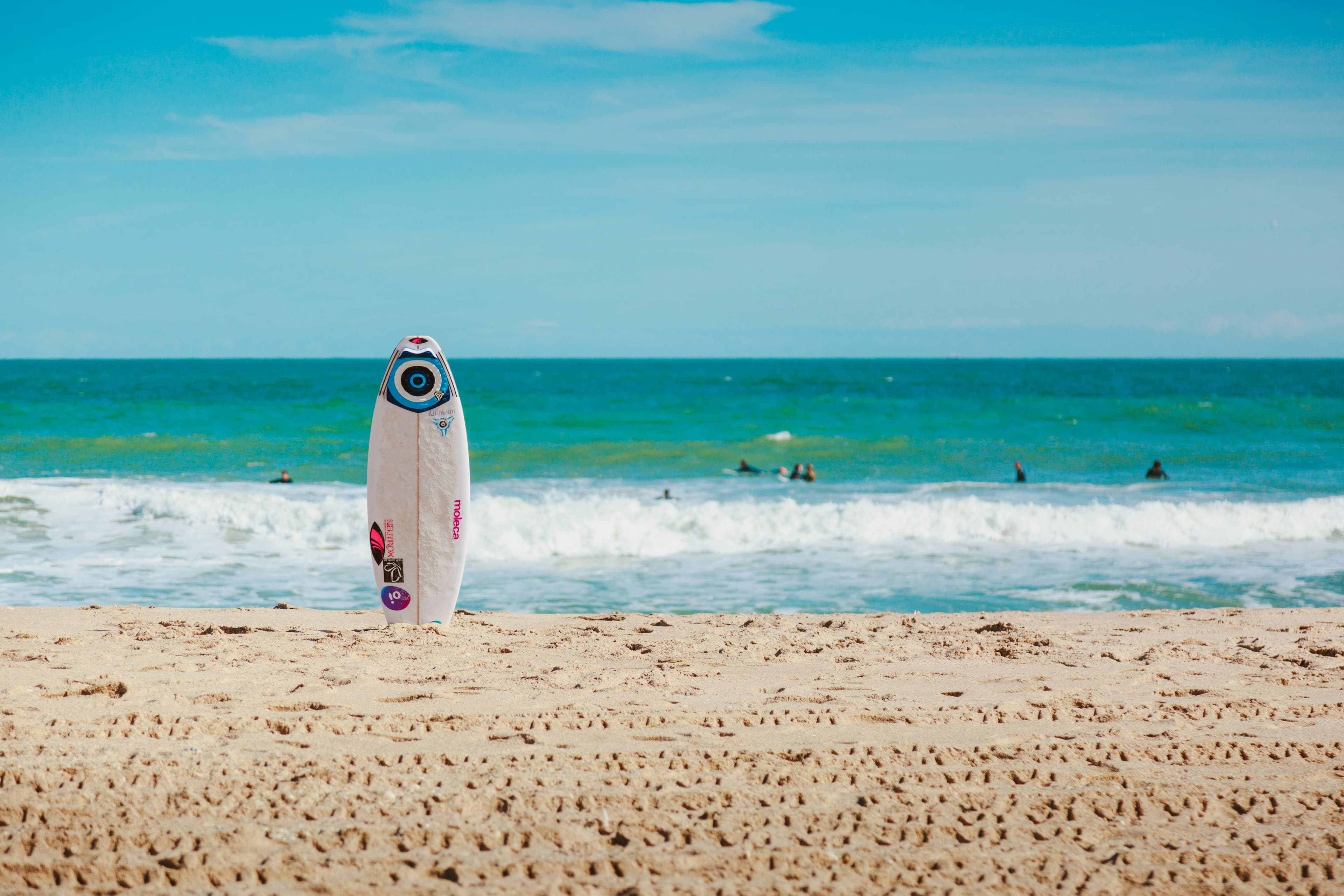 A surfboard standing in the sand at the water's edge