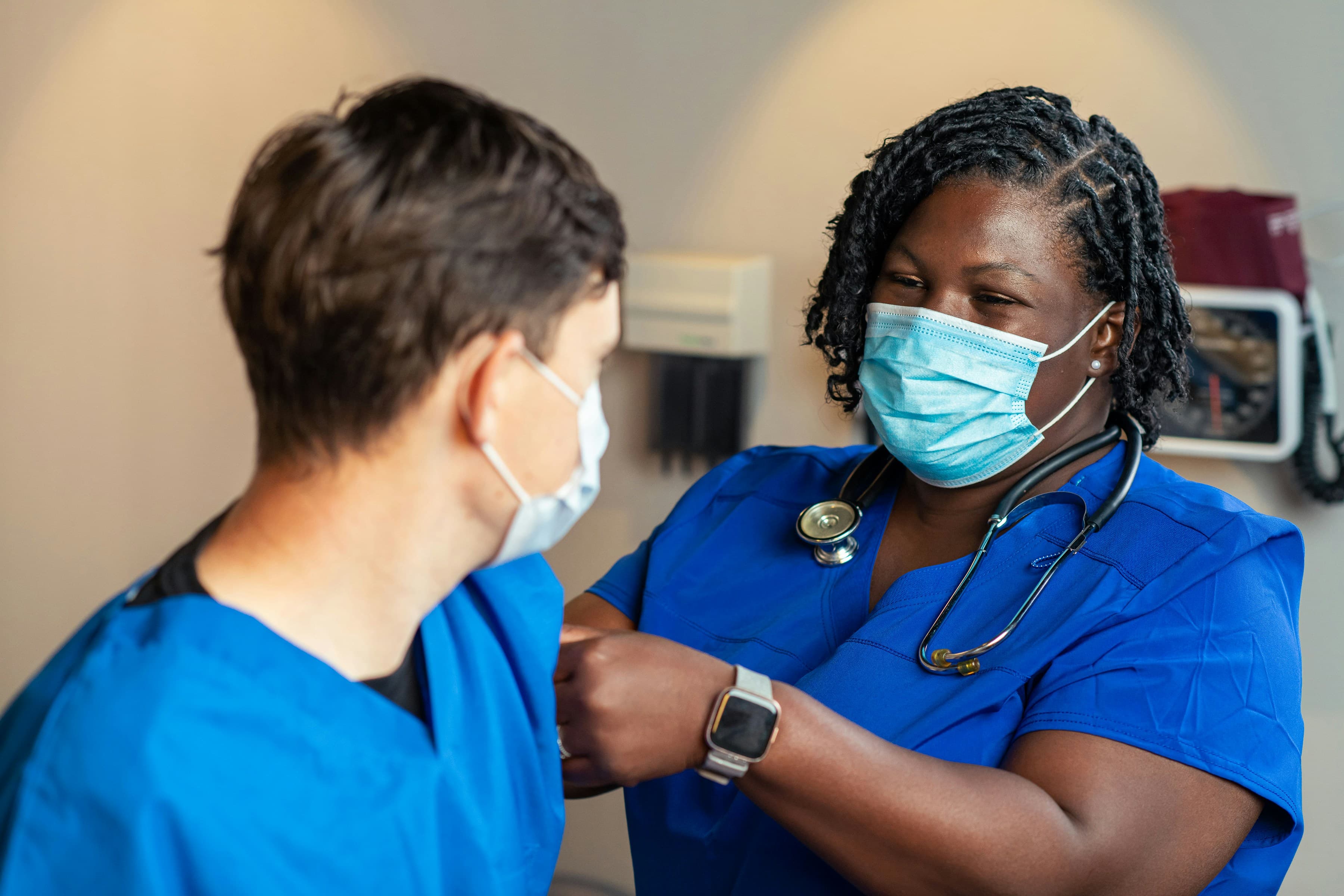 A nurse checking in with a patient who wears a health-monitoring smartwatch