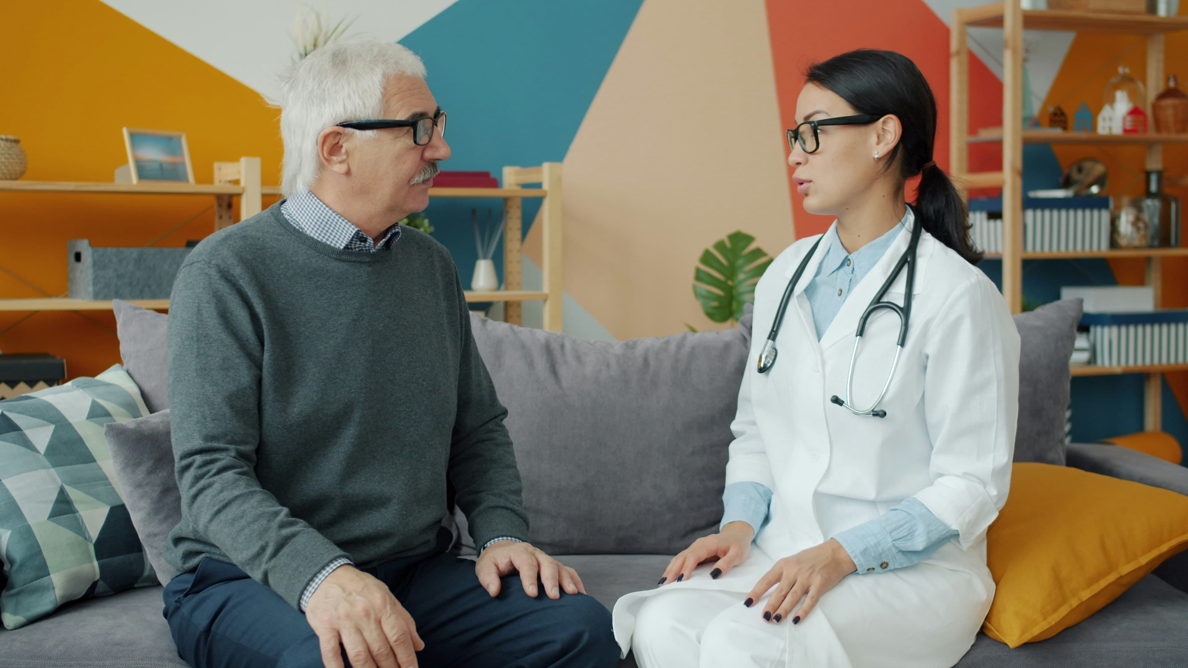 A doctor sitting with an older patient, listening closely