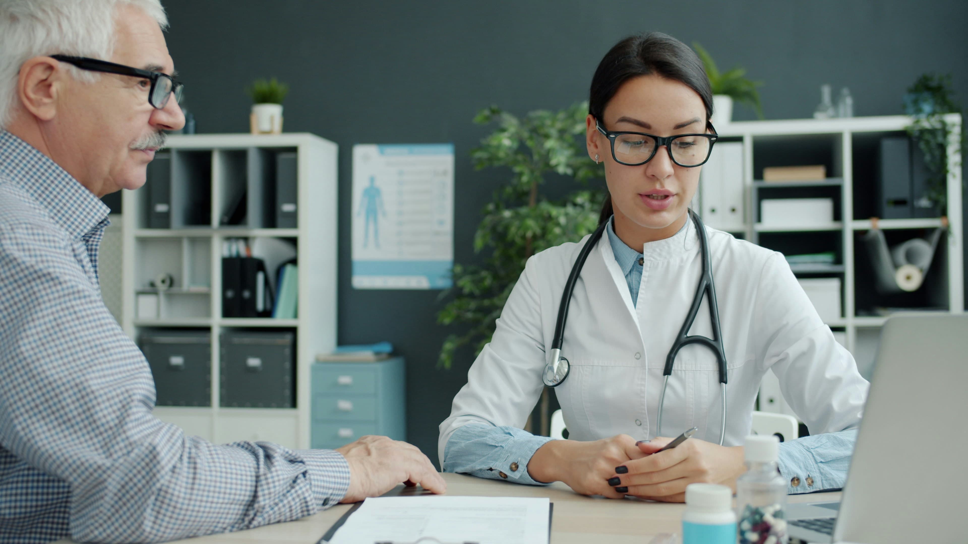 A doctor in conversation with an older patient in a bright office