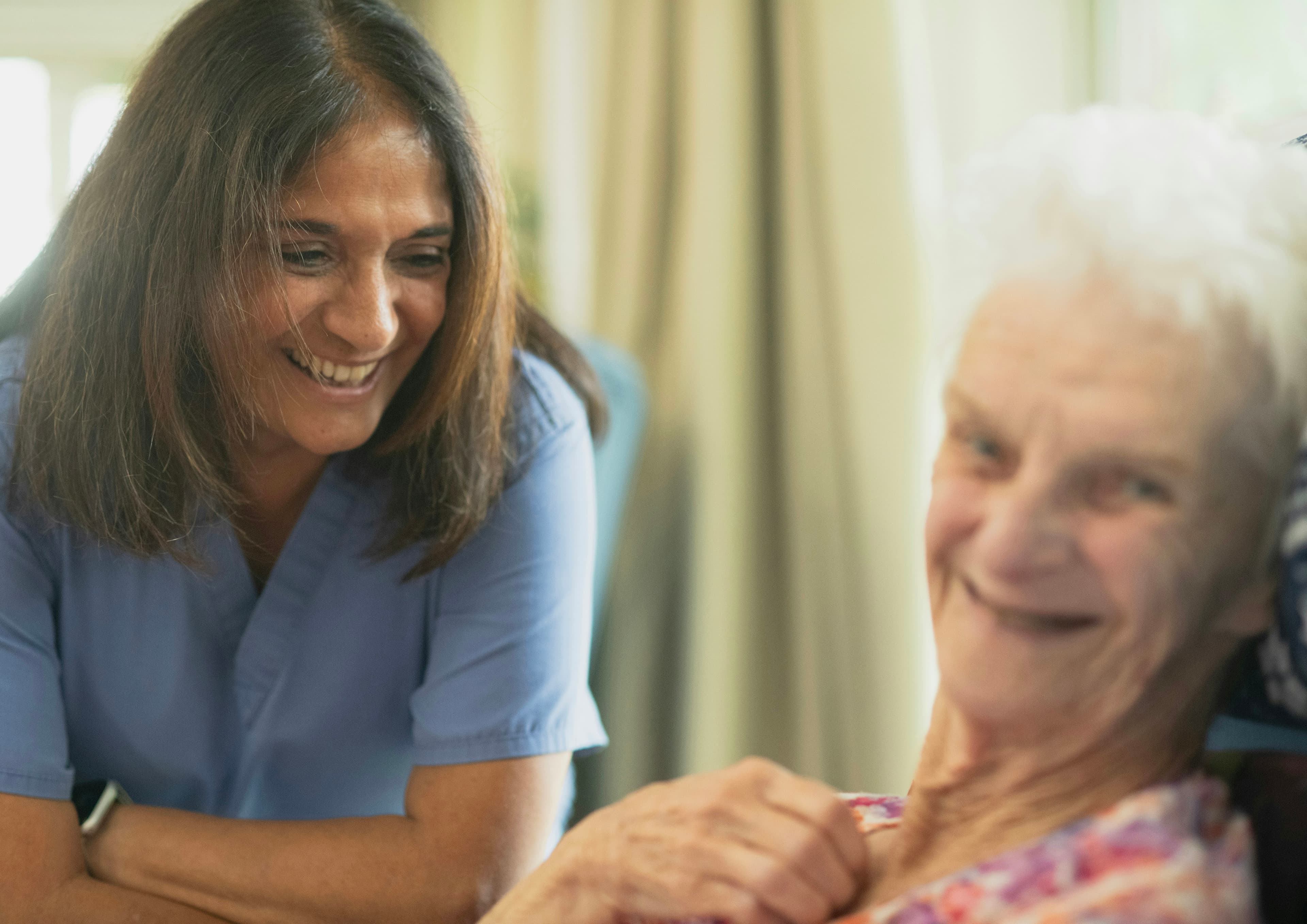 A caregiver smiling and spending time with an older patient